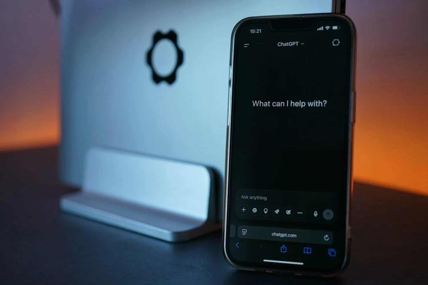 Phone displays chatgpt, next to laptop.