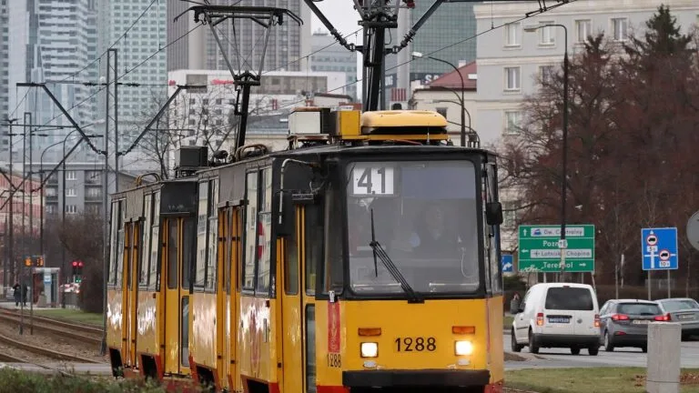 Żółto-czerwony tramwaj linii 41 jadący al. Niepodległości w Warszawie, w pobliżu siedziby GUS.