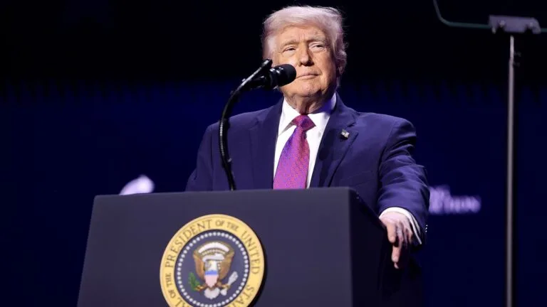 Donald Trump przemawia do publiczności za mównicą z pieczęcią prezydenta USA podczas wiecu w Arizonie.