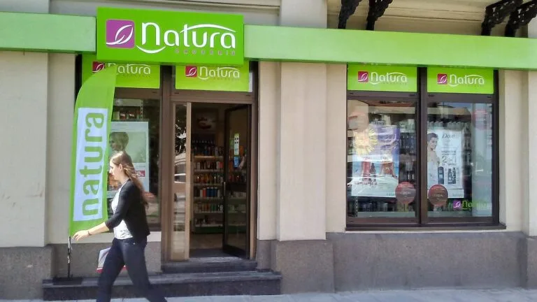 Sklep Drogerii Natura w Tomaszowie Mazowieckim; przed wejściem przechodzi kobieta, a na zielonych szyldach widać logo sieci.