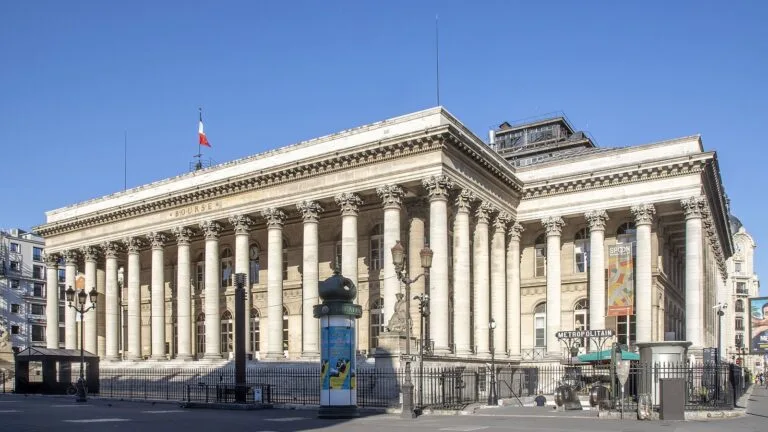 Pałac Brongniarta w Paryżu, dawna siedziba giełdy papierów wartościowych, z kolumnami i flagą Francji na dachu.