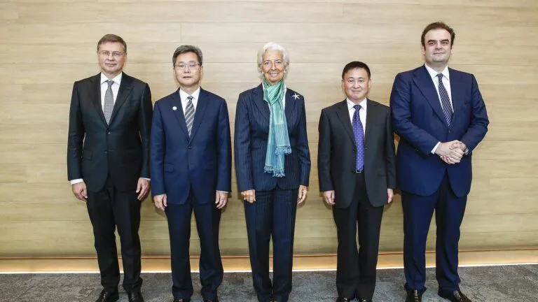 Christine Lagarde (w środku) wśród pięciu uczestników jesiennych zebrań MFW i Banku Światowego, na tle drewnianej ściany.