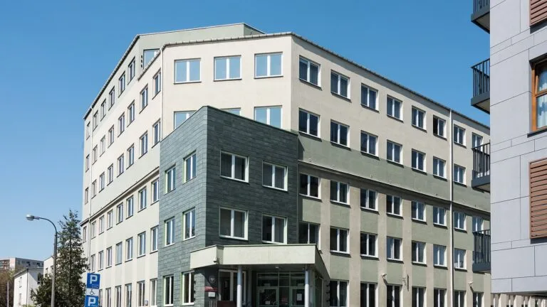 Budynek siedziby Państwowej Inspekcji Pracy przy ul. Barskiej w Warszawie, widok z ulicy w słoneczny dzień