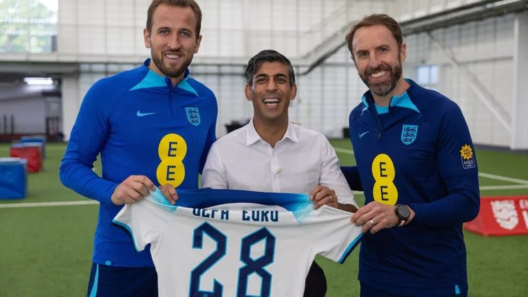 Harry Kane i Gareth Southgate z premierem Rishim Sunakiem, który trzyma koszulkę reprezentacji Anglii z numerem 28.