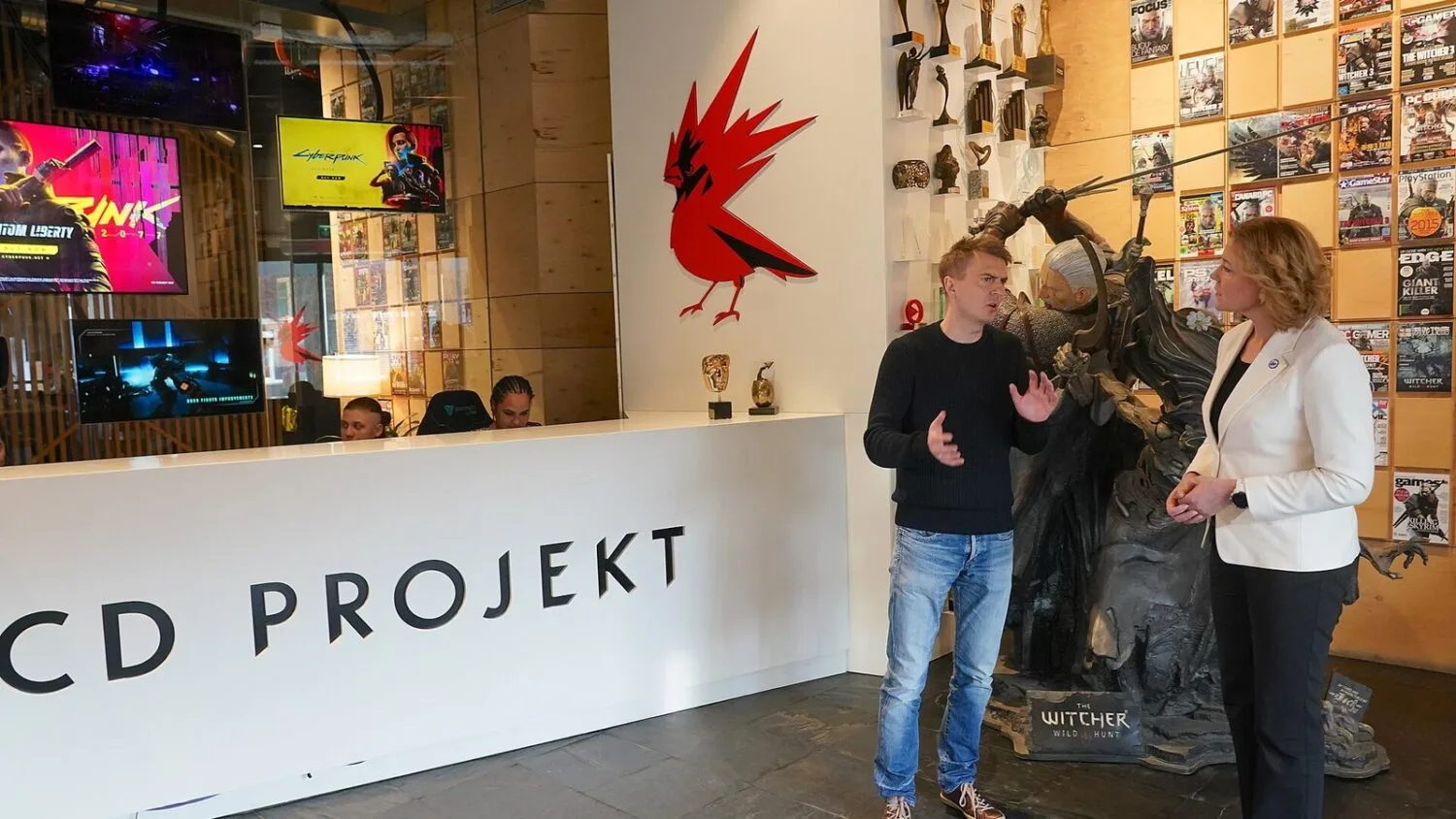 Michał Nowakowski, współzałożyciel i joint CEO CD Projektu, rozmawia z Henną Virkkunen w siedzibie firmy, obok figury…