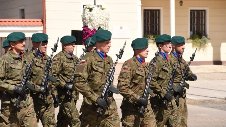 Żołnierze w polowych mundurach i zielonych beretach maszerują podczas uroczystości Święta Wojska Polskiego w Białymstoku.